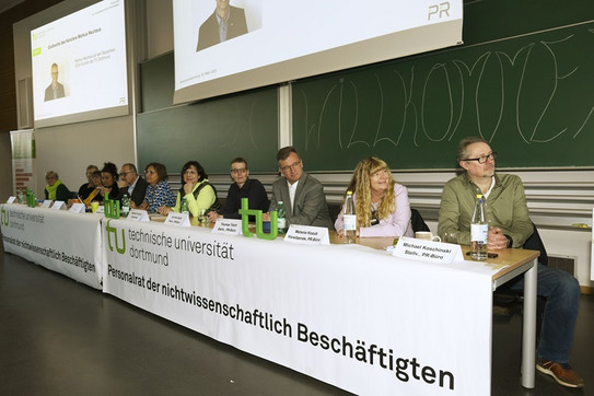 Podium mit 10 Personen und einer Rednerin