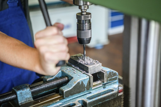 Ein Auszubildender zum Industriemechaniker bedient einen großen Metallbohrer.